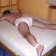 A boy is resting on the bed and he is wearing only diaper.