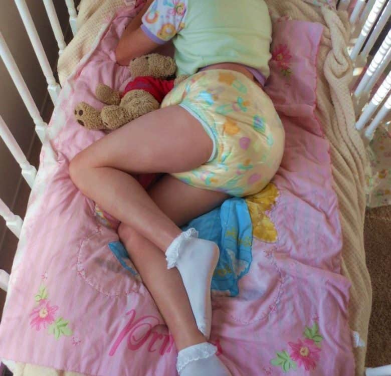 A little girl is napping in a baby swing while wearing a diaper.