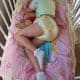 A little girl is napping in a baby swing while wearing a diaper.