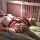 A Baby Man is laying on the bed, looking like a baby girl. He is lying there for a picture session.