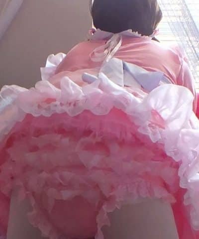 Standing on the ground in a frill baby gown and donning a white stocking and diaper