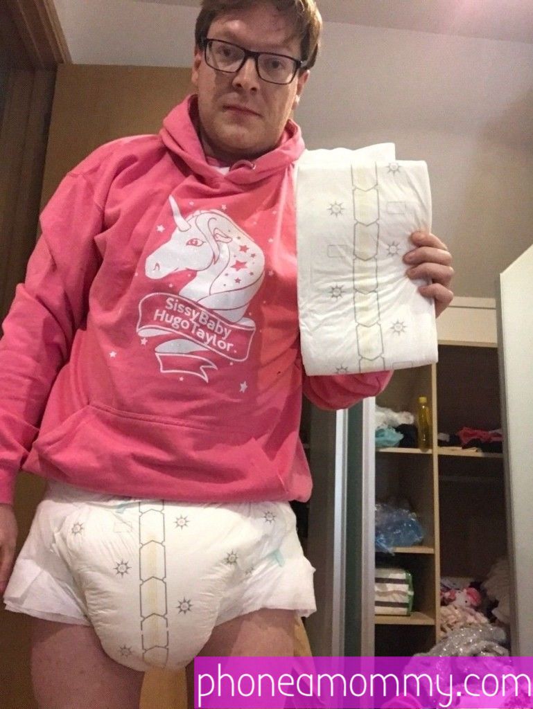 A man who loves diapers is standing on the ground while donning a pink dress and a diaper.