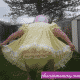 The yellow frill gown-clad Sissy With Diaper lady is standing in the garden.