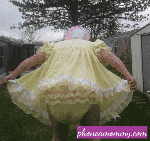 The yellow frill gown-clad Sissy With Diaper lady is standing in the garden.